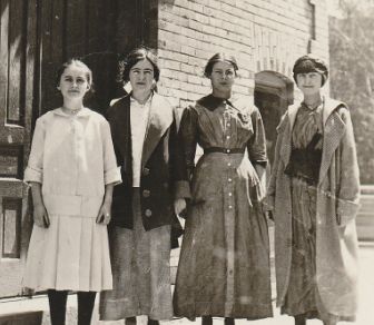 Annella as a teenager with three other women, standing outside a building.